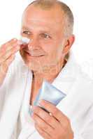 Male cosmetics - senior man apply facial cream
