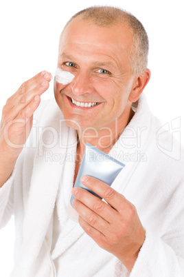 Male cosmetics - senior man apply facial cream