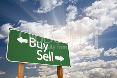 Buy, Sell Green Road Sign Against Clouds