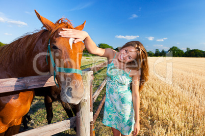 horse and blond girl in paddock on summers