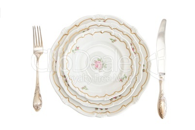 Dinner set with three plates, knife and fork isolated