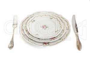 Dinner set with three plates, knife and fork isolated