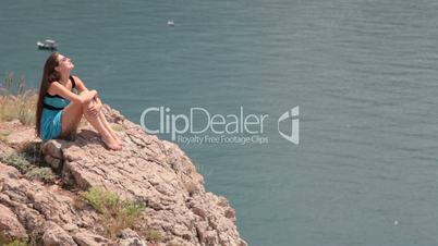 young woman resting on the edge of  cliff by the sea
