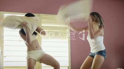 Young adult women fighting with pillows