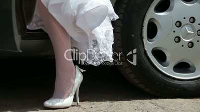 feet of  bride in  wedding dress leaving of  car