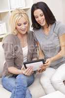 Two Young Women Using Tablet Computer At Home on Sofa