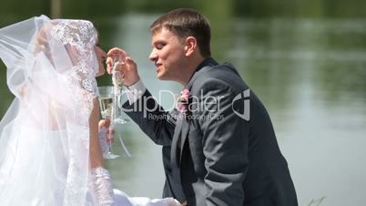 newlyweds by the lake with champagne