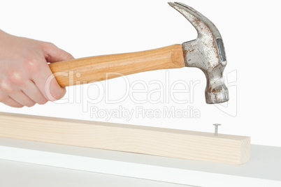 Hammer driving a nail into a wooden board