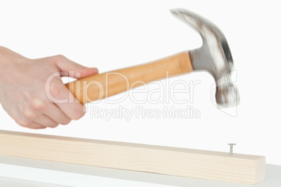 Hand holding a hammer to drive a nail