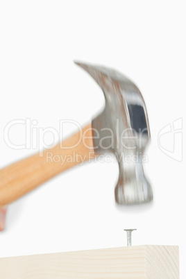 Close up of a hammer driving a nail into a board