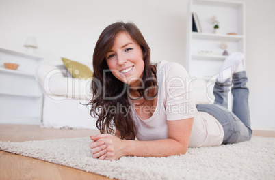 Beautiful brunette woman posing while lying on a carpet