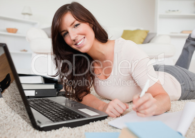 Young brunette woman relaxing with her laptop while writing on a