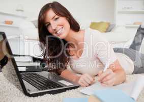 Young brunette woman relaxing with her laptop while writing on a