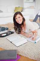Young good looking woman writing on a notebook while lying on a