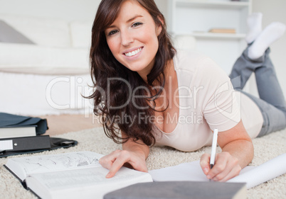 Young charming woman writing on a notebook while lying on a carp