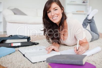 Young gorgeous woman writing on a notebook while lying on a carp