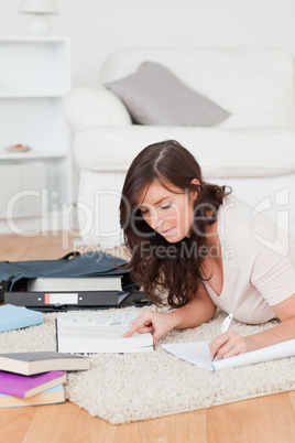 Young beautiful female writing on a notebook while lying on a ca