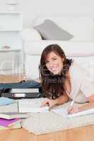 Young attractive female writing on a notebook while lying on a c