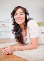 Beautiful brunette female using headphones while lying on a carp