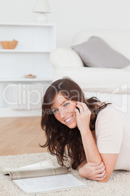 Young gorgeous woman reading a magazine while lying on a carpet