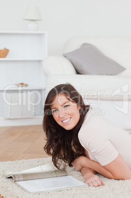 Young good looking woman reading a magazine while lying on a car