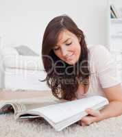 Attractive woman reading a magazine while lying on a carpet