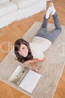 Pretty woman reading a magazine while lying on a carpet