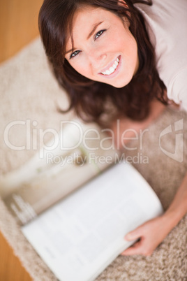 Cute woman reading a magazine while lying on a carpet