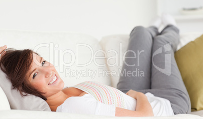 Attractive brunette woman posing while lying on a sofa