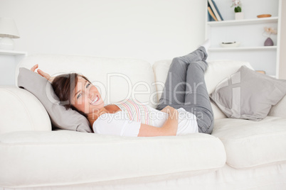 Charming brunette woman posing while lying on a sofa