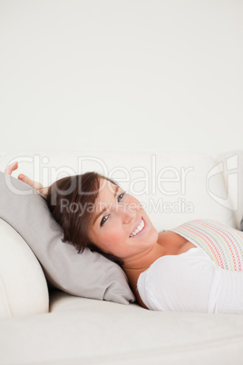 Cute brunette woman posing while lying on a sofa