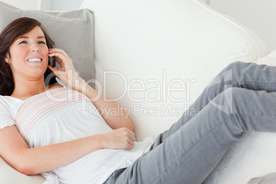 Good looking brunette female on the phone while lying on a sofa