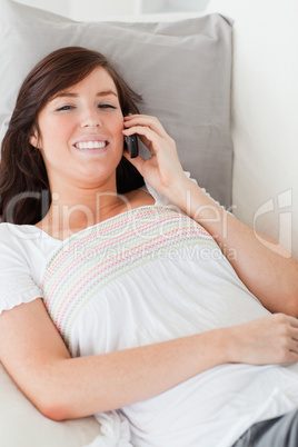 Attractive brunette female on the phone while lying on a sofa