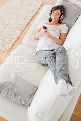 Attractive brunette woman on the phone while lying on a sofa