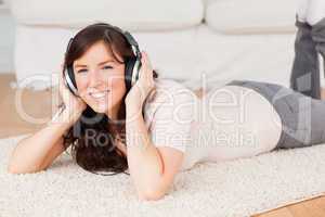 Attractive brunette woman using headphones while lying on a carp