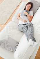 Young cute female having a rest and reading a book while lying o
