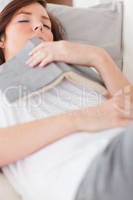 Young charming female having a rest and reading a book while lyi