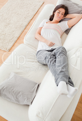 Young charming female having a rest while lying on a sofa