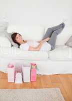 Young charming female posing with her shopping bags while lying