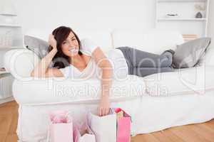 Young gorgeous female posing with her shopping bags while lying