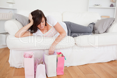 Young cute woman posing with her shopping bags while lying on a