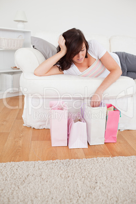 Young pretty woman posing with her shopping bags while lying on