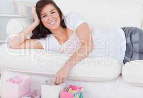 Young attractive woman posing with her shopping bags while lying