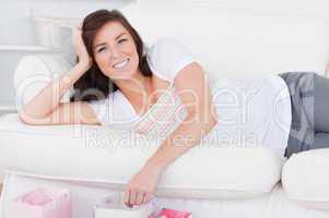 Young charming woman posing with her shopping bags while lying o