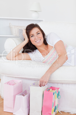 Young lovely woman posing with her shopping bags while lying on