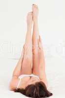 Beautiful brunette female stretching her legs while lying