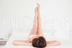 Attractive brunette female stretching her legs while lying