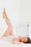 Pretty brunette female stretching her legs while lying