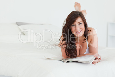 Pretty female reading a magazine while lying