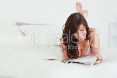 Cute female reading a magazine while lying